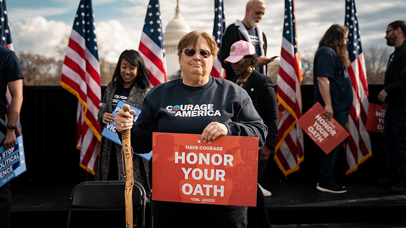 image of a woman holding a sign that says "Honor Your Oath"